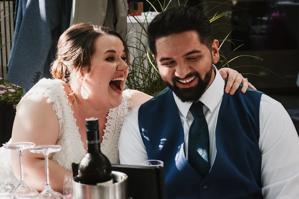 Bernhard and Lisa laughing together at the table at their wedding.