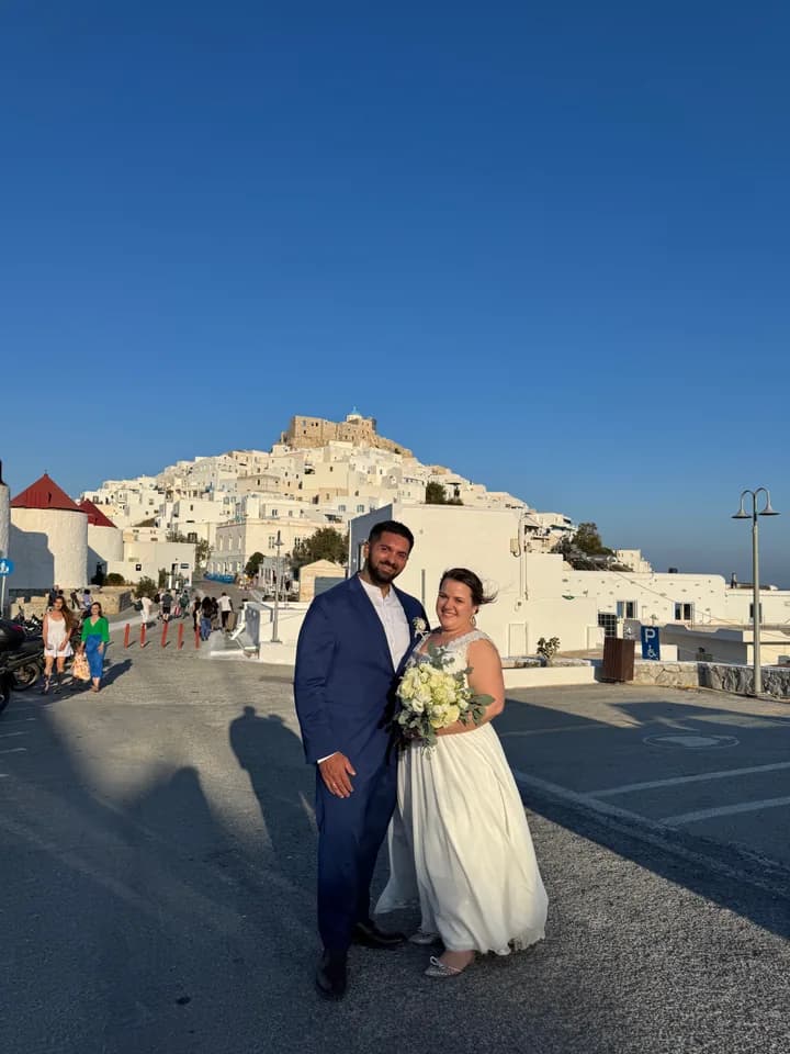 Bernhard and Lisa on a square below a white hilltop village in the sunlight.