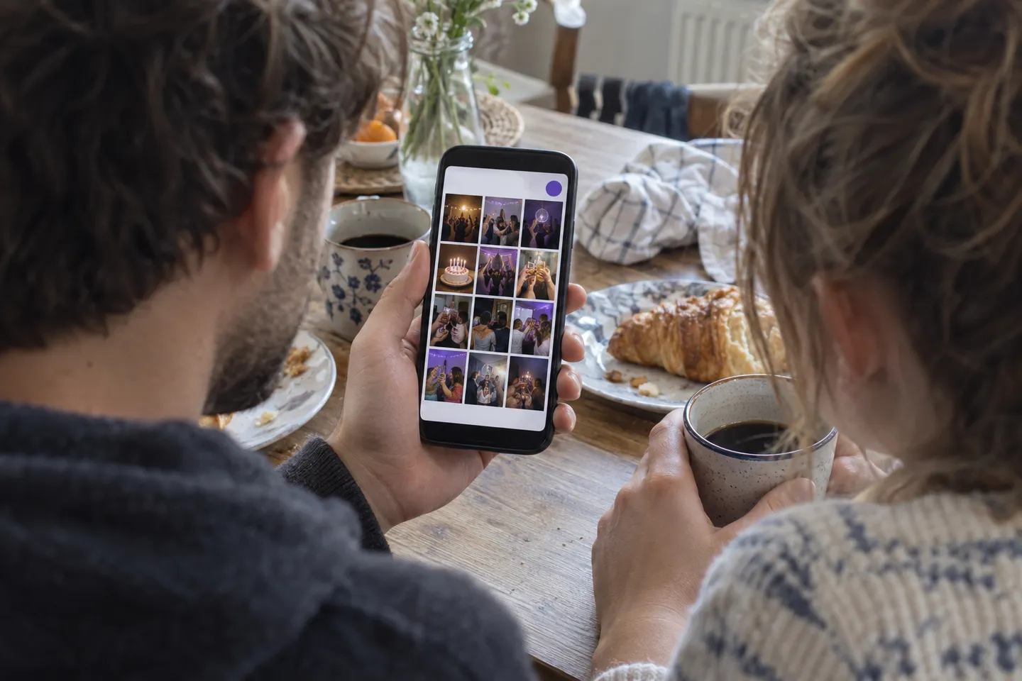 Two guests at the breakfast table looking through the photos of the evening as an album on a phone